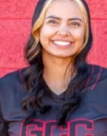 A woman smiling for the camera in front of a red wall.