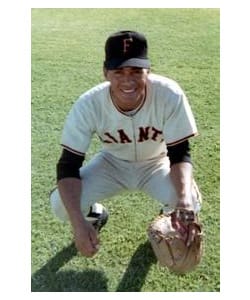 A baseball player kneeling on the field with his glove.