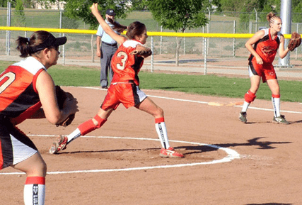 A girl swinging at a ball during a softball game.