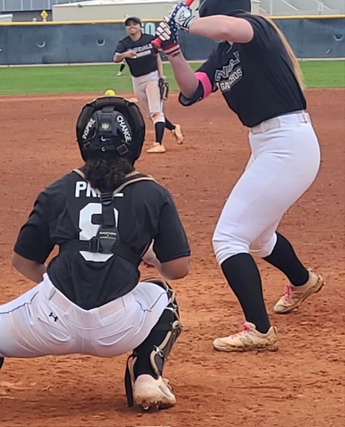 A softball player is about to catch the ball.