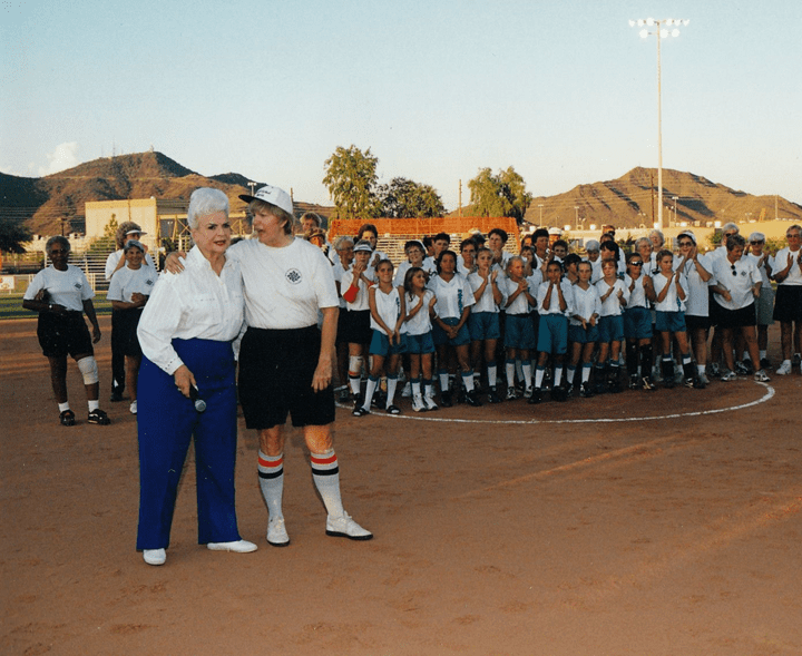 Two women standing next to each other on a field.